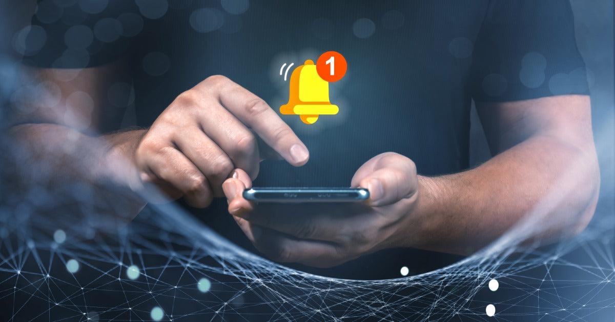 A person holds a smartphone and taps the screen. A yellow bell with the number 1 floats above the screen.